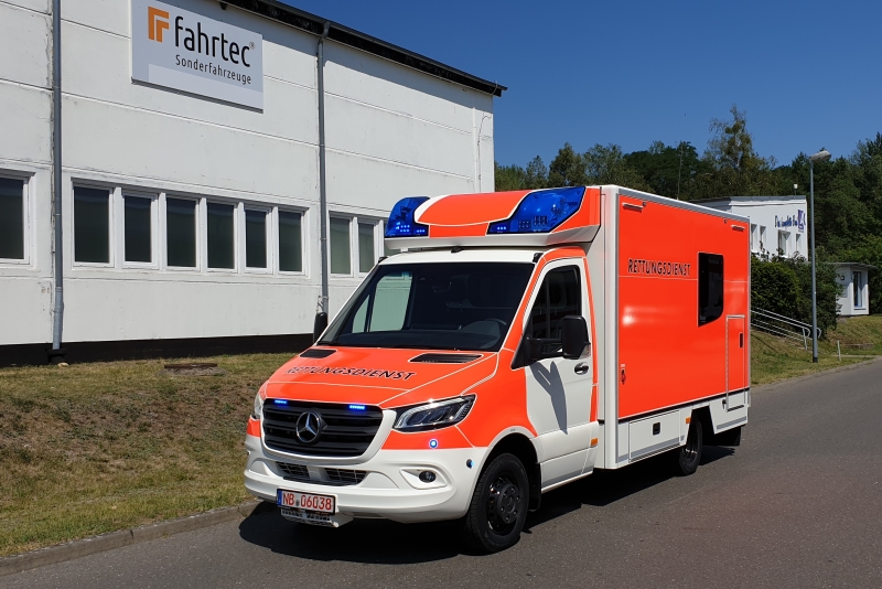 Abbildung zeigt einen orangenen Rettungswagen in Kastenform der Marke Mercedes Benz